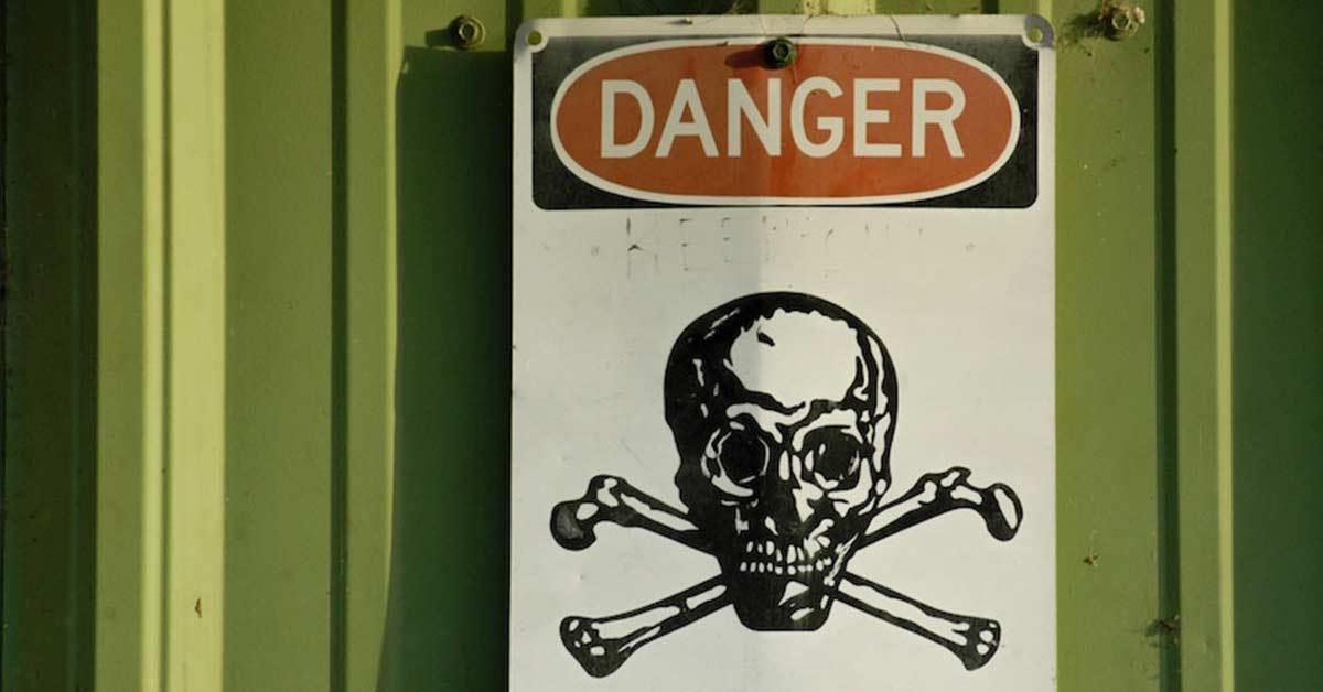 A sign with "DANGER" written in red and white at the top and a black skull and crossbones graphic below, indicating a hazardous area. The sign is mounted on a green surface.