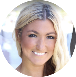 A woman with long, blonde hair and a white smile is looking at the camera. The background is slightly blurred.